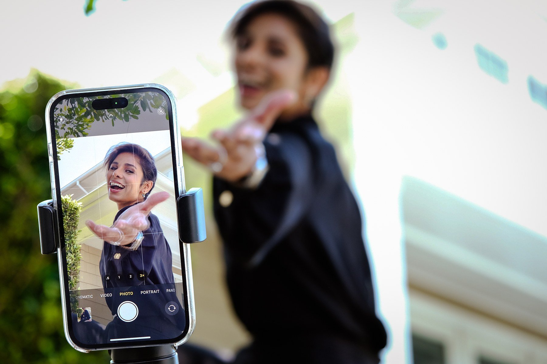 Parmita laughing and reaching toward her phone camera on a tripod