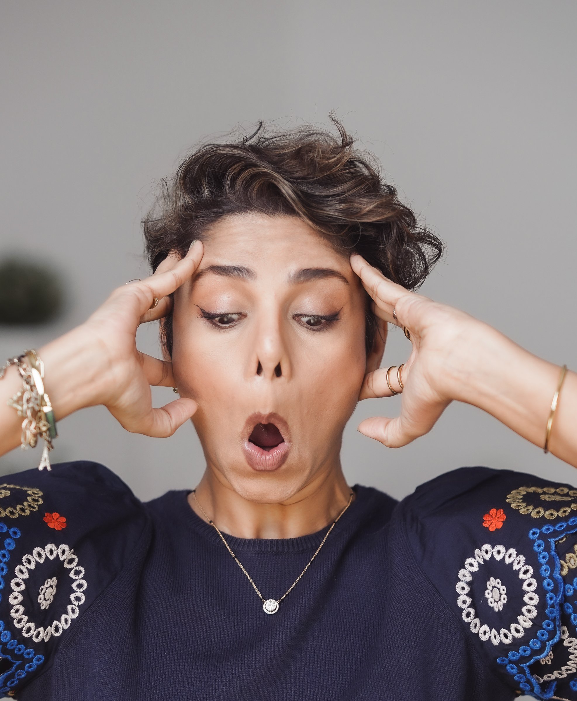 A raised-brow expression held against fingertip pressure